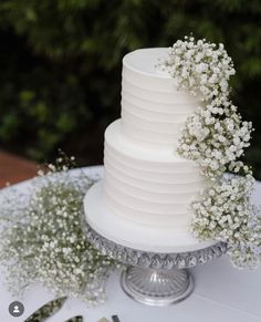 a white wedding cake with baby's breath flowers on top is sitting on a table