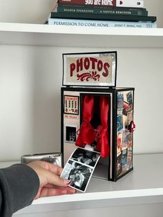 a person is holding an old fashioned photo in front of a box with photos inside