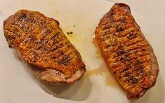 two pieces of cooked meat sitting on top of a white plate next to each other