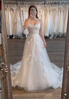 a woman taking a selfie in front of a mirror wearing a white wedding dress