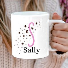 a woman is holding a coffee mug with the letter s on it and stars around her