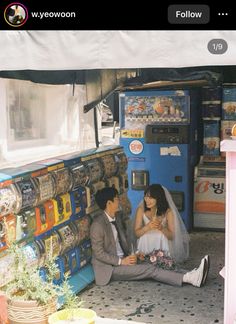 two people sitting on the ground in front of a vending machine