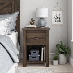 a bedroom with a bed, nightstand and lamp on the side table in front of it