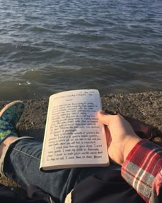 someone is reading a book by the water