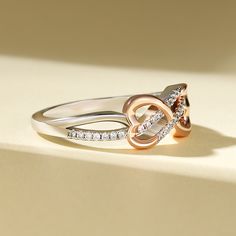 Embrace the intertwining beauty of love and elegance with our sterling silver ring. The open heart and twisted knot design symbolize a bond that is strong, yet tender. The rose gold heart adds a touch of warmth and romance to this exquisite piece. Let this ring grace your hand as a reminder of the intertwining paths of love and connection. The intricate design speaks to the complexity and beauty of relationships, while the heart symbolizes the depth of emotion and affection shared between souls. Wear this sterling silver ring as a symbol of enduring love and unity, a testament to the intertwining of hearts and the strength found in togetherness.Carat Weight: 0.3 ctStone Size: 1 mmStone Type: Jeulia® StoneNumber of Stones: 30 Stone Color: Diamond WhiteStone Shape: RoundWeight: 3.1 gWidth: 1 Elegant Rose Gold Heart Ring For Mother's Day, Sterling Silver Infinity Rings For Valentine's Day, Silver Infinity Ring For Valentine's Day, Adjustable Elegant Heart Ring For Promise, Elegant Adjustable Heart Ring, Sterling Silver Infinity Heart Wedding Ring, Sterling Silver Infinity Heart Ring For Wedding, Infinity Heart Ring For Valentine's Day Anniversary, Valentine's Day Infinity Heart Ring For Anniversary