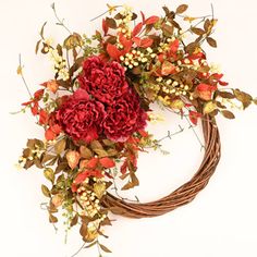 a wreath with red flowers and greenery on it