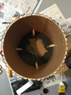 a brown bowl sitting on top of a table covered in papers and glues next to scissors