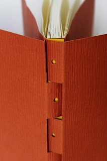 an open orange book with yellow buttons on the cover and pages are folded in half