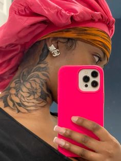 a woman wearing a pink phone case with tattoos on her arm and neck, holding up a cell phone