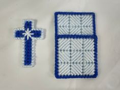 a crocheted blue and white cross next to it's matching pinhole