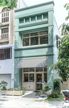 a green building with an awning on the front and side of it's windows