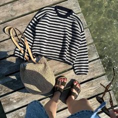 a woman's feet and purse on a wooden dock