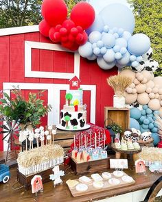 a farm themed birthday party with balloons, cake and desserts on a table in front of a red barn