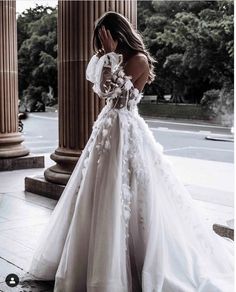 a woman in a white wedding dress standing on the sidewalk with her hands to her face