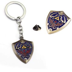 two metal key chains with the legend of zelda emblem on them, one is silver and the other is blue