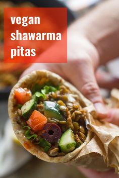 a person holding a pita filled with meat and veggies