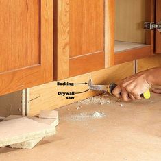 a man is using a grater to clean the floor in front of his kitchen cabinets