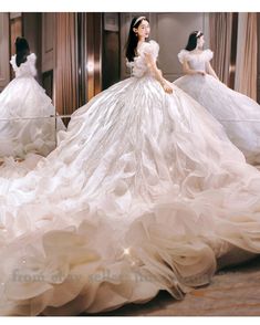 a woman in a white wedding dress standing next to other mannequins wearing gowns