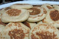 several pita breads sitting on top of each other in a white dish with brown spots