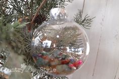 a glass ornament hanging from a tree filled with rocks and pine cones in front of a white wooden wall