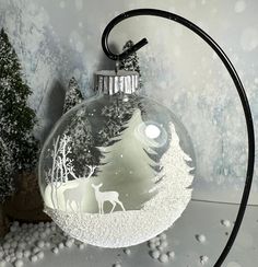 a glass ornament with a deer in the snow on it's side