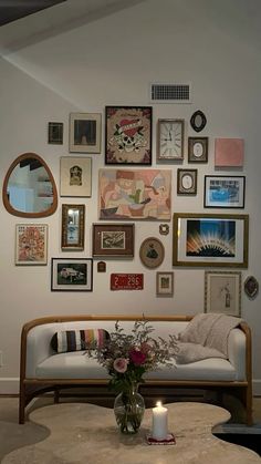 a living room filled with furniture and lots of framed pictures on the wall above it