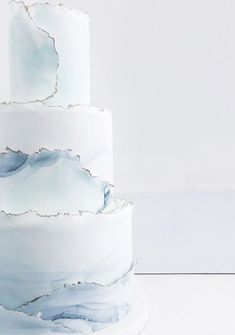 a three tiered white cake with blue marbled icing