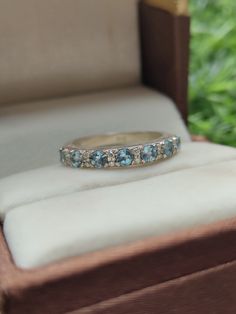 a wedding band with blue topaz sits in a box