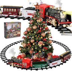 a christmas tree with trains around it and a train on the tracks next to it