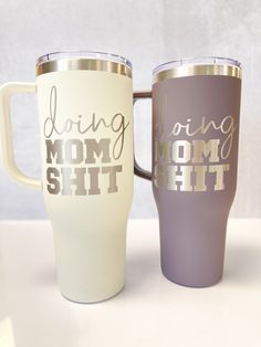 two coffee mugs sitting next to each other on top of a white countertop