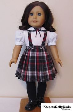 the doll is wearing a plaid dress and bow tie with black tights on it