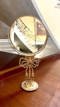 a mirror sitting on top of a wooden table in front of a stair case next to a banister