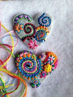 two heart shaped brooches sitting next to each other on top of a table