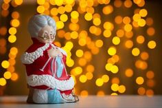 an old lady figurine sitting on a table in front of a christmas tree