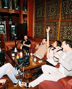 several people sitting around a table with drinks in front of them and one person raising his hand