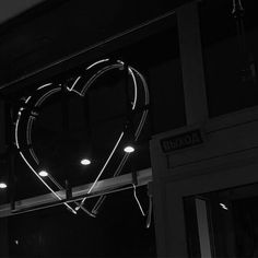 a heart shaped neon sign hanging from the side of a building