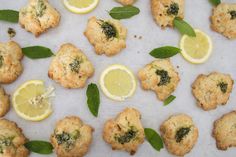 lemon and herb cookies are arranged on a sheet of wax paper with leaves around them