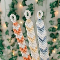 three knitted candy canes in front of a christmas tree