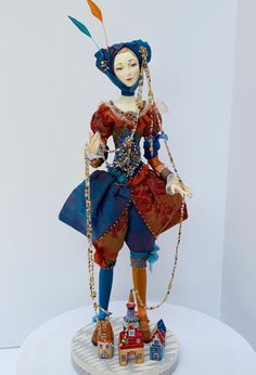 a figurine is displayed on a white pedestal with a blue dress and red hat