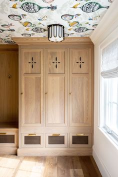 an empty room with wooden cupboards and painted wallpaper on the ceiling above it