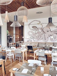 an empty restaurant with tables and chairs in front of a large octopus painting on the wall