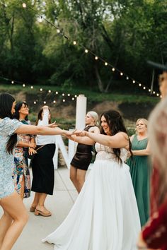 a group of people standing around each other on a sidewalk with their arms in the air