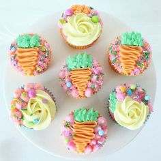 cupcakes decorated with icing and flowers on a plate