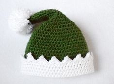 a crocheted green and white hat with pom - pom