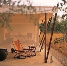 an outdoor area with chairs, table and grill in the middle of it's natural setting