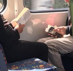 two people sitting on a train reading books