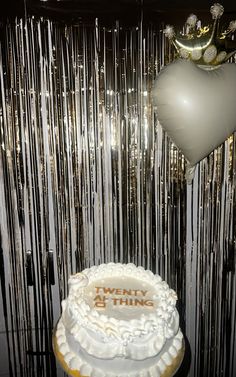 a white cake sitting on top of a table next to a balloon and streamers