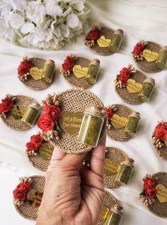 a hand is holding a jar with flowers on it next to several small jars that have hearts in them