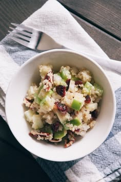 a white bowl filled with food sitting on top of a table next to a fork