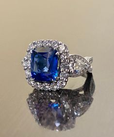 a blue and white diamond ring sitting on top of a table